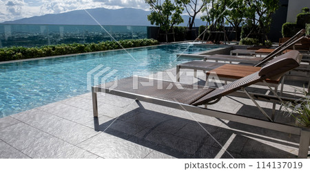 Picture of a sun bed chair on the edge of a hotel or resort rooftop swimming pool Picture of a sun bed chair on the edge of a hotel or resort rooftop swimming pool 114137019
