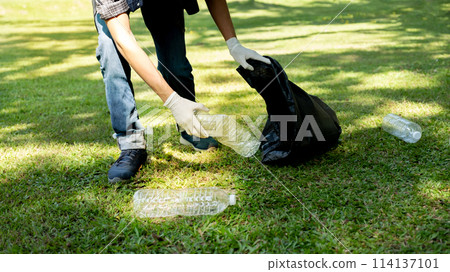 Hand holding plastic bottle waste, picking up trash and putting it in the black garbage bag at the Park on Environmental Earth day 114137101