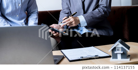 The real estate agent explains the business contract, rent, purchase, mortgage, a loan, or home insurance to the women buyer The real estate agent explains the business contract, rent, purchase, mortgage, a loan, or home insurance to the women buyer 114137155