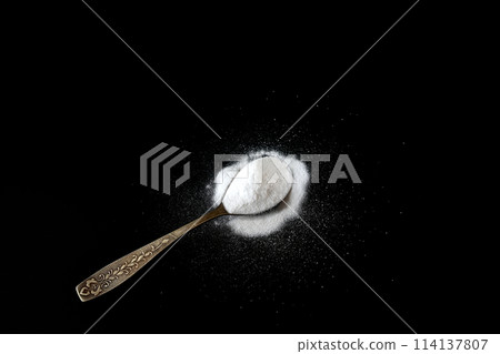 Baking soda in a spoon on a black background. Baking soda in a spoon on a black background. 114137807