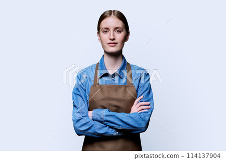 Portrait of young smiling confident woman in apron on white background 114137904