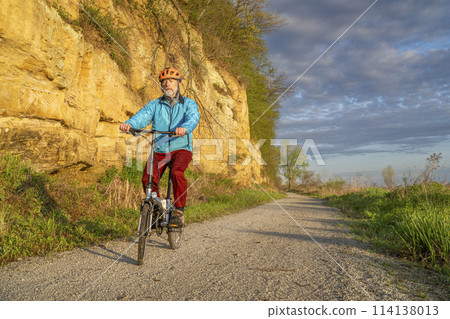 male cyclist riding a folding bike on Steamboat Trace, bike trail converted from an abandoned railroad, near Peru, Nebraska, springtime morning scenery 114138013