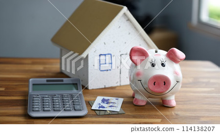 Calculator with piggy bank against home background Calculator with piggy bank against home background 114138207