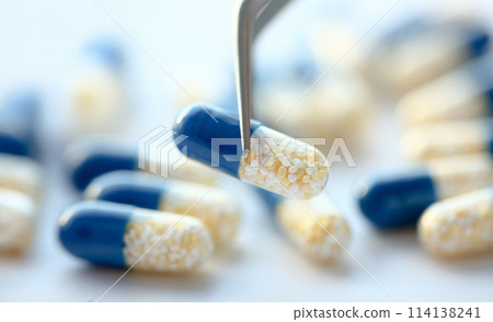 Arm lifting up pill with tweezers closeup Arm lifting up pill with tweezers closeup 114138241