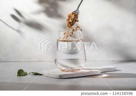 Protein collagen pink powder, fruits and vegetables powder, food supplement in a glass with water 114138596