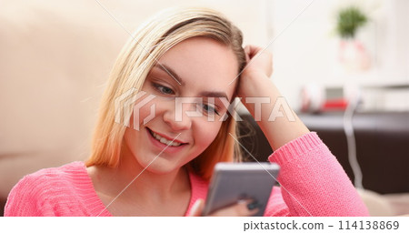 young pretty blond womansit on sofa hold smartphone in hands young pretty blond womansit on sofa hold smartphone in hands 114138869