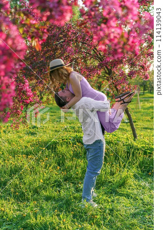 Young married couple embraces in park, surrounded by blooming trees Young married couple embraces in park, surrounded by blooming trees 114139043