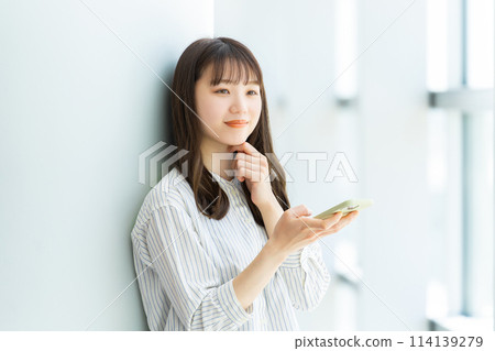Smiling young woman using a smartphone 114139279