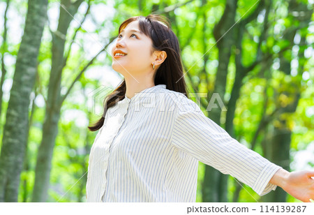 Young woman taking a deep breath in the greenery 114139287