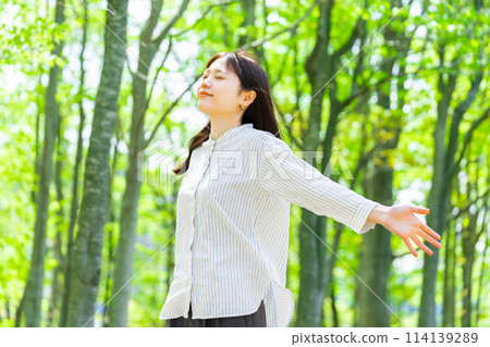 Young woman taking a deep breath in the greenery 114139289