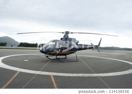 Blue and Orange Helicopter on Runway in Forested Area 114139338