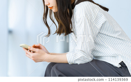 Business woman operating a smartphone Business woman operating a smartphone 114139369
