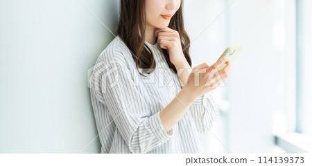 一位年輕女子微笑著使用智慧型手機 一位年輕女子微笑著使用智慧型手機 114139373