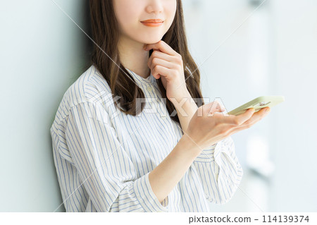 一位年輕女子微笑著使用智慧型手機 一位年輕女子微笑著使用智慧型手機 114139374