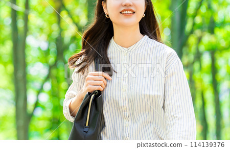 走在綠樹中的微笑的女商人 走在綠樹中的微笑的女商人 114139376