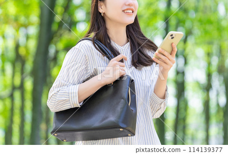 操作智慧型手機的微笑的女商人 操作智慧型手機的微笑的女商人 114139377