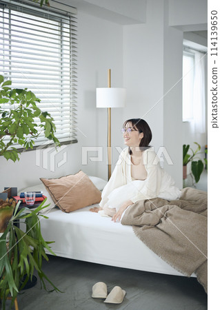 A woman in her 20s wakes up and tries to get out of bed A woman in her 20s wakes up and tries to get out of bed 114139650
