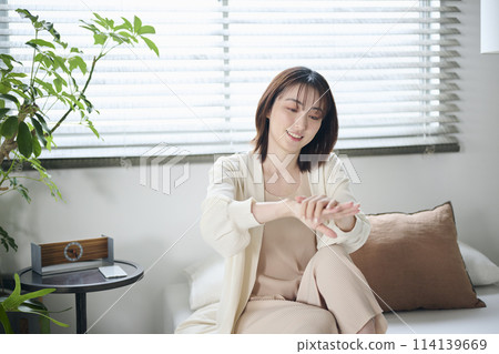 A woman in her twenties doing hand care in bed 114139669