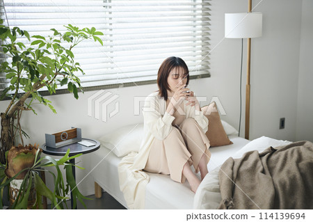 20多歲女子躺在床上喝水 20多歲女子躺在床上喝水 114139694