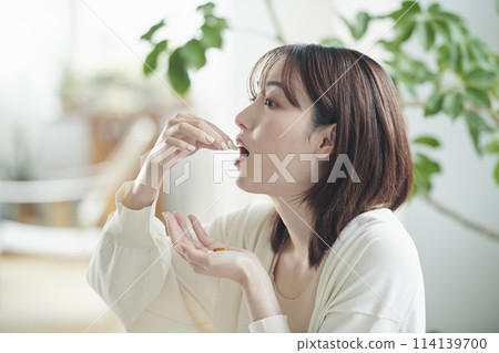 A woman in her twenties drinking supplements in bed 114139700