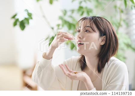 A woman in her twenties drinking supplements in bed A woman in her twenties drinking supplements in bed 114139710