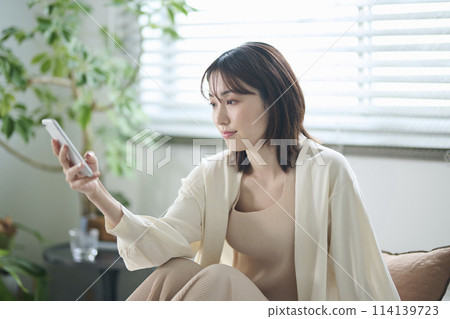 A woman in her twenties looking at her smartphone in bed A woman in her twenties looking at her smartphone in bed 114139723