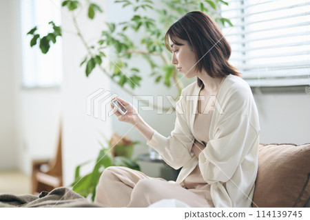 一名 20 多歲的女性躺在床上看智慧型手機 一名 20 多歲的女性躺在床上看智慧型手機 114139745