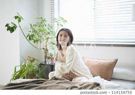 A woman in her 20s sitting on a bed 114139759