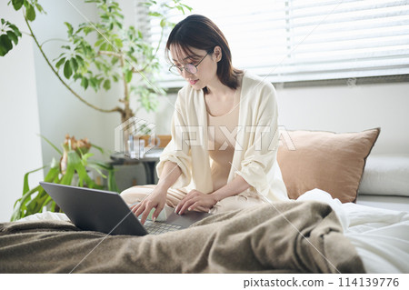 A woman in her twenties using a laptop in bed A woman in her twenties using a laptop in bed 114139776