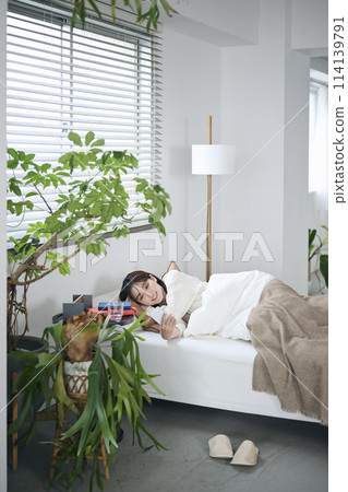 一名 20 多歲的女性躺在蒲團上，看著她的智慧型手機 114139791