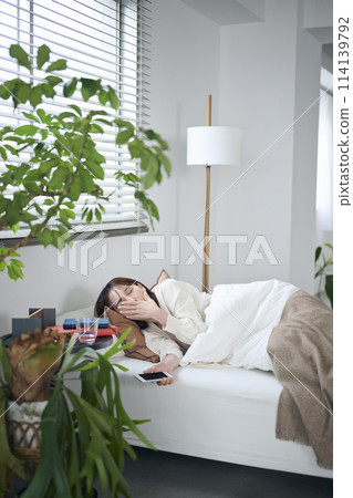 一名20多歲的女性早上醒來打哈欠 一名20多歲的女性早上醒來打哈欠 114139792