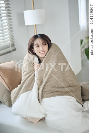 A woman in her 20s wrapped in a futon in bed, morning 114139867