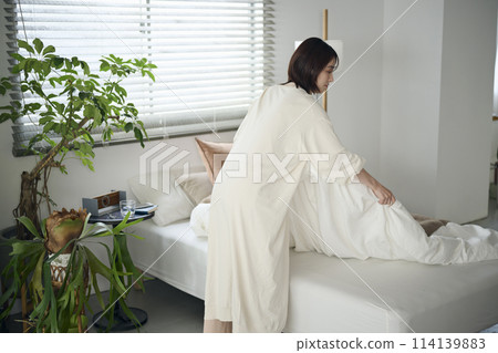 一個20多歲的女子正在整理床鋪 114139883
