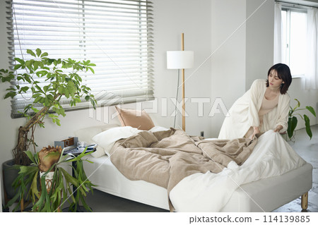 A woman in her twenties making her bed 114139885