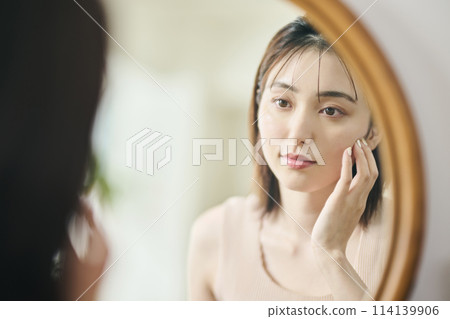 Woman in her 20s touching her own skin, reflection, mirror 114139906