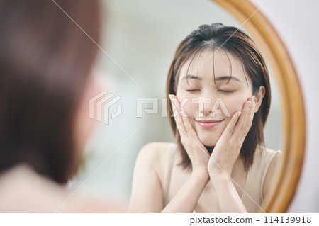 A woman in her twenties doing skin care in the mirror A woman in her twenties doing skin care in the mirror 114139918