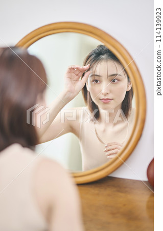 一名20多歲的女性在鏡子前梳理頭髮 114139923