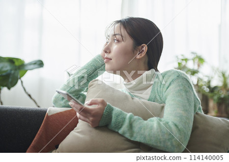 一位女士在沙發上放鬆時看著智慧型手機 114140005