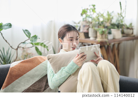 一位女士在沙發上放鬆時看著平板電腦 114140012