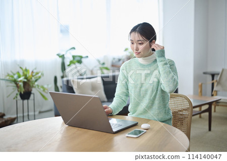 A woman in her twenties having an online meeting in the living room A woman in her twenties having an online meeting in the living room 114140047