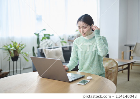 A woman in her twenties having an online meeting in the living room A woman in her twenties having an online meeting in the living room 114140048
