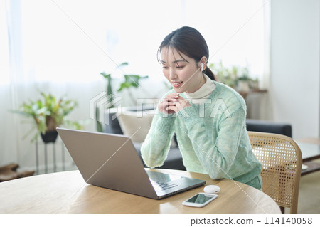 A woman in her twenties having an online meeting in the living room 114140058