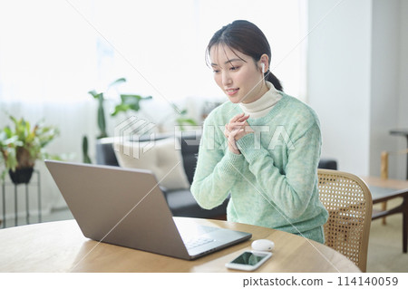 A woman in her twenties having an online meeting in the living room 114140059