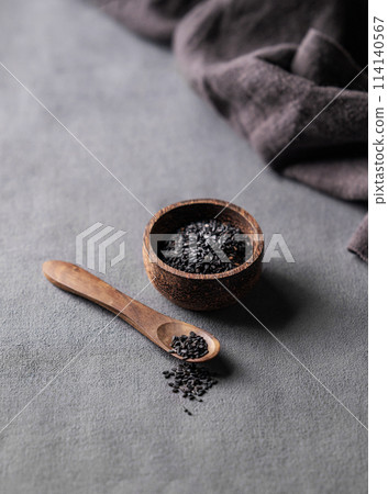 Black sesame seeds in a wooden bowl on a dark background with spoon. Black sesame seeds in a wooden bowl on a dark background with spoon. 114140567
