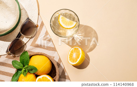 Summer layout with lemonade, fresh citrus fruits, hat and sunglasses on a beach towel Summer layout with lemonade, fresh citrus fruits, hat and sunglasses on a beach towel 114140968