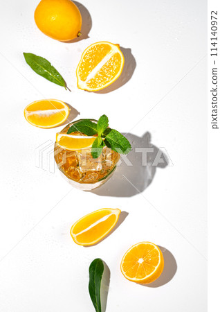 Flat lay of Iced tea with lemon and mint on white background with a shadow and citrus fruits. Flat lay of Iced tea with lemon and mint on white background with a shadow and citrus fruits. 114140972