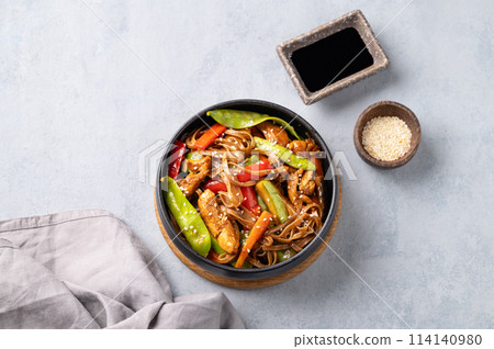 Stir-fry with soba noodles, meat and vegetables on a light background. Stir-fry with soba noodles, meat and vegetables on a light background. 114140980
