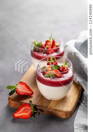 Panna cotta with strawberry and cream in glasses with fresh berries on a wooden board  114140990