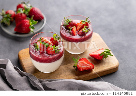 Strawberry and cream panna cotta in glasses with fresh berries on a wooden board Strawberry and cream panna cotta in glasses with fresh berries on a wooden board 114140991