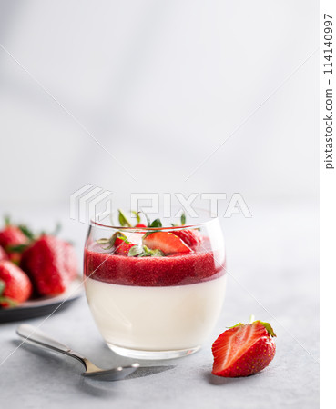 Panna cotta with strawberry and cream in glass with fresh berries on a light background close up  114140997